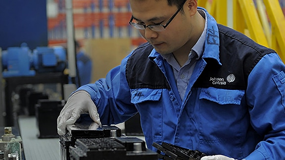 A person wearing glasses and gloves working on a machine.