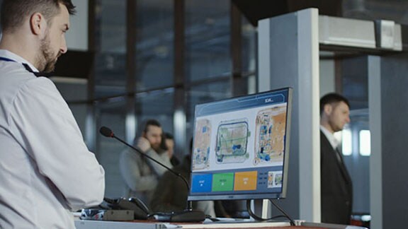 An airport security guard looking at a monitor displaying luggage being scanned