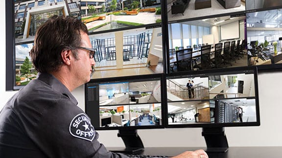 A security guard examining a monitor displaying video surveillance footage