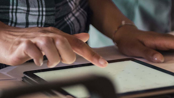 Close-up of a person operating a tablet laid down on a table