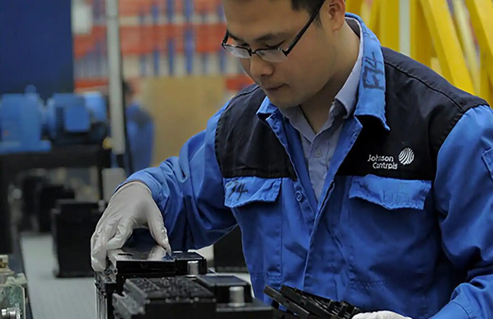 Man in a Johnson Controls jumpsuit working at a machine